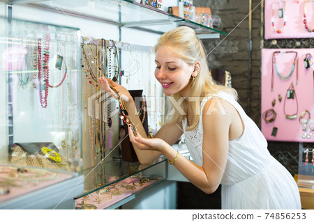 girl customer choosing necklace. 74856253