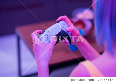 Girl with next gen controller in her hands playing games at home. 74856312