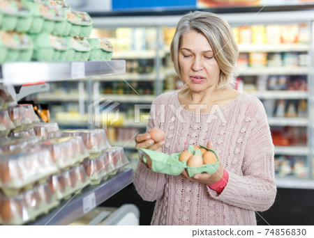 Mature woman choosing eggs Mature woman choosing eggs 74856830