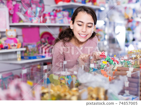 schoolgirl delighted with choosing lollipop in store 74857005