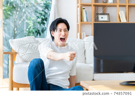 年輕人在客廳裡看電視 年輕人在客廳裡看電視 74857091