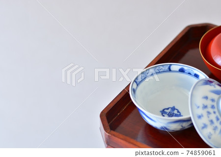 有盒蓋的茶碗在一個高腳的集合裝飾古色古香的伊万里市商品陶瓷。 有盒蓋的茶碗在一個高腳的集合裝飾古色古香的伊万里市商品陶瓷。 74859061