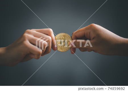 Two hands holding and pulling golden bitcoin. Two hands holding and pulling golden bitcoin. 74859692