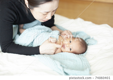 Mother changing baby clothes Mother changing baby clothes 74860401