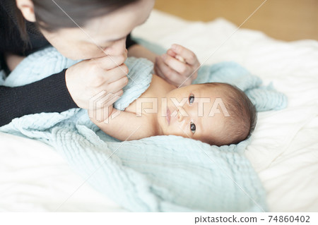 Mother changing baby clothes Mother changing baby clothes 74860402
