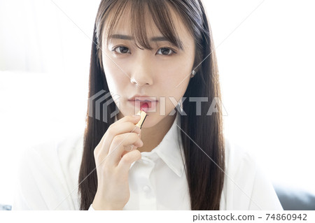 A woman applying lipstick 74860942