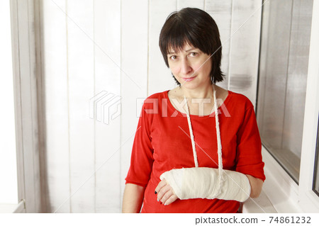 a broken arm. Close-up of the plaster. A lady in a red jacket with a bright manicure. exercises to restore and strengthen the muscles. damage to the bones. 74861232