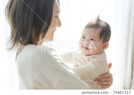 A cute baby being held by its mother A cute baby being held by its mother 74861317