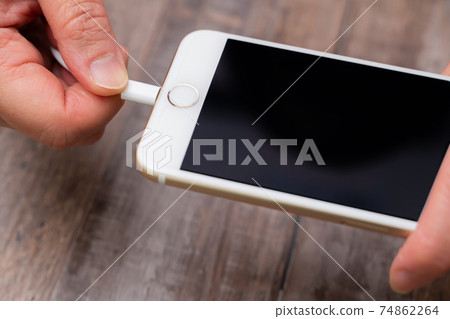 A woman charging her smartphone A woman charging her smartphone 74862264