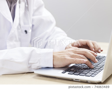 hands of a doctor typing on laptop computer hands of a doctor typing on laptop computer 74863489