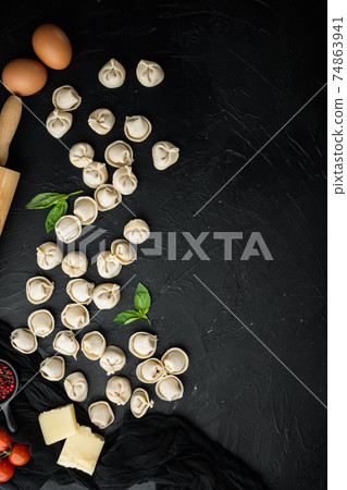 Italian tortellini with fresh ricotta leaves and tomatoes, on black background , top view flat lay , with copyspace and space for text 74863941