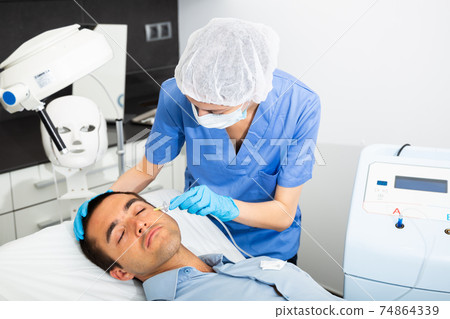 Man receiving carboxytherapy procedure at beauty clinic Man receiving carboxytherapy procedure at beauty clinic 74864339