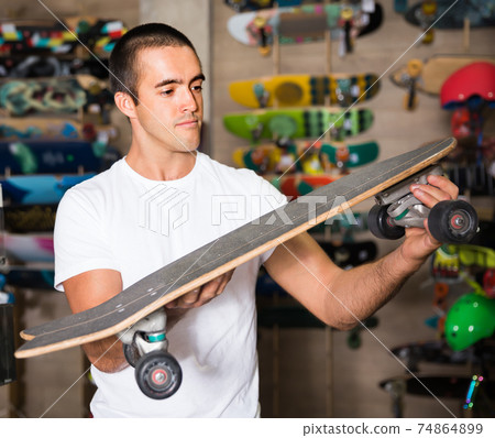 Happy young man choosing skateboard 74864899