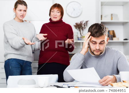 Frustrated man with papers on background with discontented family 74864951
