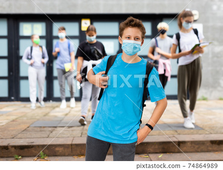 Young student in a protective mask going to college down city street 74864989