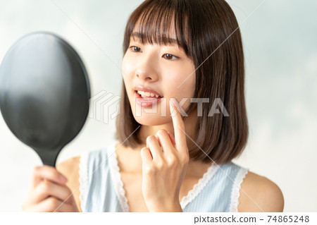 Late teenage girls looking in the mirror 74865248