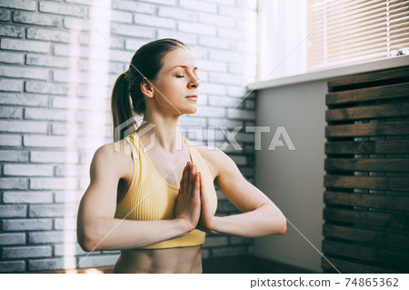 A blonde girl is resting after a fitness class and meditating. The concept of sports and a healthy lifestyle. Yoga, meditation A blonde girl is resting after a fitness class and meditating. The concept of sports and a healthy lifestyle. Yoga, meditation 74865362