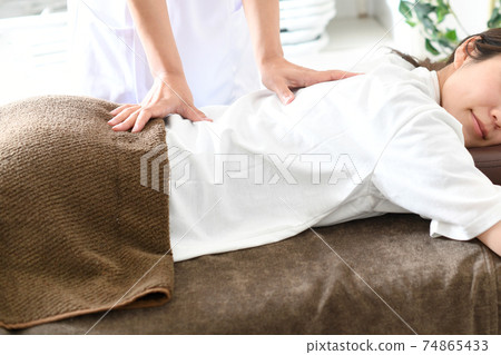 Young woman receiving massage (manipulative treatment) in bed Young woman receiving massage (manipulative treatment) in bed 74865433