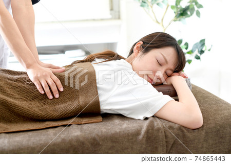 年輕女子在床上接受按摩(手法治療) 年輕女子在床上接受按摩(手法治療) 74865443