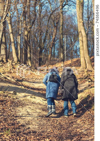 Two girls go uphill. Woman hiking through green woods vegetation, going uphill. Tourism and travel concept. toned Two girls go uphill. Woman hiking through green woods vegetation, going uphill. Tourism and travel concept. toned 74866496