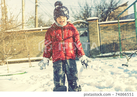 Excited Child playing with snow on white snow background. smiling boy catching snowflakes. Funny little boy in blue winter clothes walks during a snowfall. Outdoors winter activities for kids. toned Excited Child playing with snow on white snow background. smiling boy catching snowflakes. Funny little boy in blue winter clothes walks during a snowfall. Outdoors winter activities for kids. toned 74866551