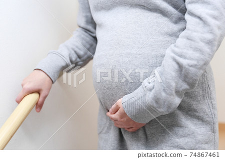 Pregnant woman going down the stairs Pregnant woman going down the stairs 74867461