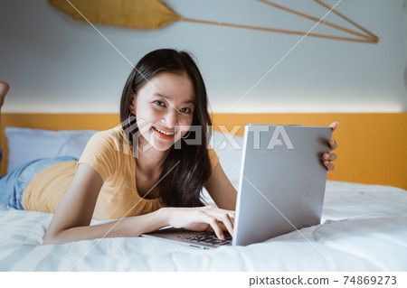 woman lying down the bed in front of her laptop. Working from home in quarantine lockdown. Social distancing Self Isolation woman lying down the bed in front of her laptop. Working from home in quarantine lockdown. Social distancing Self Isolation 74869273