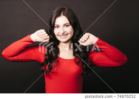Excited young woman standing clenching fists 74870252