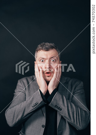 Troubled worried shocked man over black background 74870302