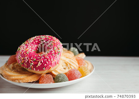 Plate with unhealthy sugary sweets, copy space Plate with unhealthy sugary sweets, copy space 74870393