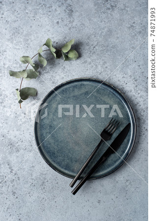 An empty plate and cutlery on a gray table. 74871993