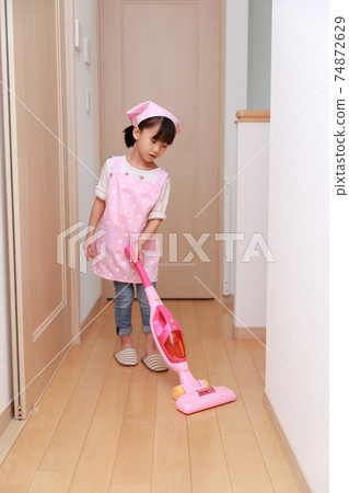 A 5-year-old girl playing housewife's housewife with a vacuum cleaner toy 74872629