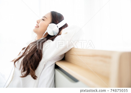 Beautiful young asian woman in headphones listening to music 74875035