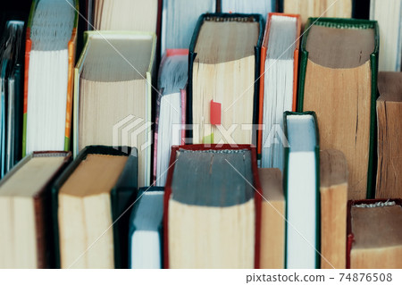 This is a lot of books standing together in several rows. Solid background of books in close-up. 74876508