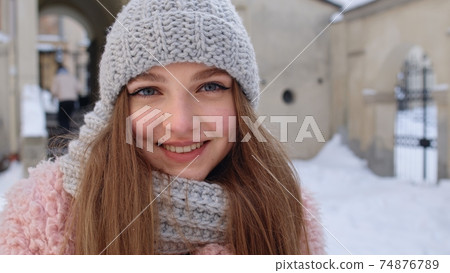 Portrait of Caucasian pretty happy girl with smile on face posing on winter citystreet background 74876789