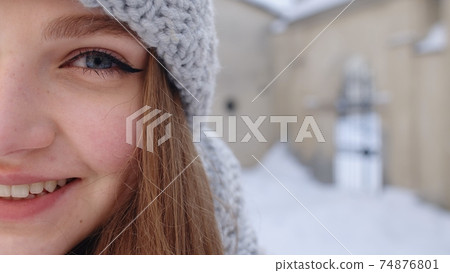Close-up of cheerful positive young woman face smiling to camera while standing outdoors in winter Close-up of cheerful positive young woman face smiling to camera while standing outdoors in winter 74876801