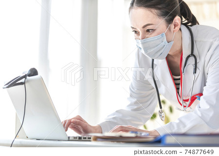 Female doctor operating a personal computer Female doctor operating a personal computer 74877649