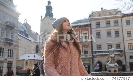 Portrait of young female girl tourist looking around, walking alone through street in old town 74877987