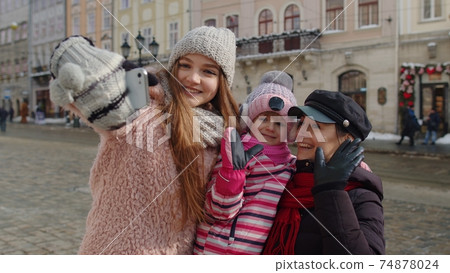 Sisters tourists taking selfie, posing, making video conferencing on mobile phone on city street Sisters tourists taking selfie, posing, making video conferencing on mobile phone on city street 74878024