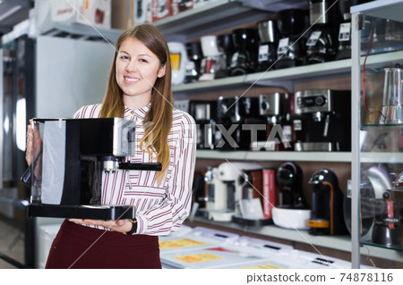 Positive saleswoman suggesting coffee brewer in shop 74878116