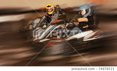 Group of people driving go-carts at racing track Group of people driving go-carts at racing track 74878513