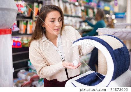Woman chooses accessories for cats in pet store Woman chooses accessories for cats in pet store 74878693