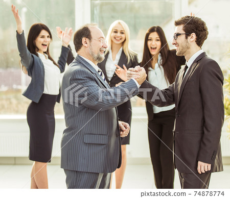 handshake of business partners on background of cheering business team handshake of business partners on background of cheering business team 74878774
