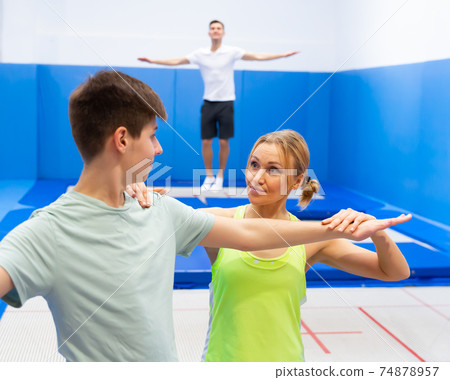 Female trampoline instructor teaching teenage boy Female trampoline instructor teaching teenage boy 74878957