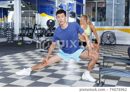 Couple stretching before workout at gym Couple stretching before workout at gym 74878962