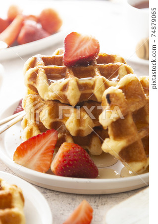 Delicious breakfast. Belgian waffles with honey and strawberries. Cup of tea white wooden background, top view. Delicious breakfast. Belgian waffles with honey and strawberries. Cup of tea white wooden background, top view. 74879065