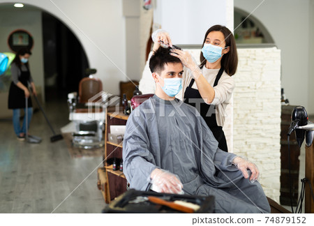 Client in mask during hair cut by professional hairdresser in mask 74879152