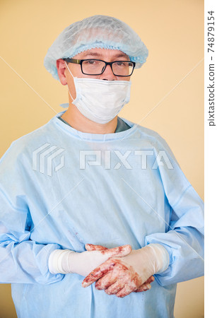 Male surgeon in medical mask standing against yellow background. 74879154