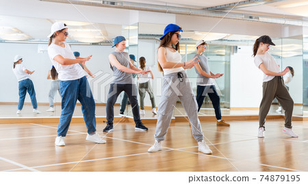 Happy smiling teenagers practicing vigorous hip hop movements in class Happy smiling teenagers practicing vigorous hip hop movements in class 74879195