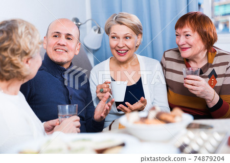 Mature women and their friend are drinking tea and talking Mature women and their friend are drinking tea and talking 74879204